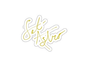 May include: A white sticker with a gold script design that reads "Set Astro". The sticker has a thin white border and is suitable for various applications.