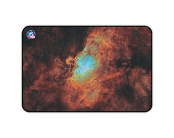 May include: Rectangular mousepad featuring a vibrant image of a nebula with shades of orange, brown, and blue. The mousepad has a black border and a small logo in the upper left corner. The design is space-themed.