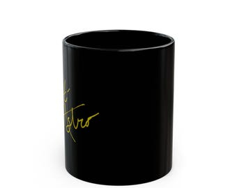 May include: A black ceramic mug with the words "Sweet Astro" in gold script. The mug is cylindrical and has a glossy finish. The text is written in a cursive font.