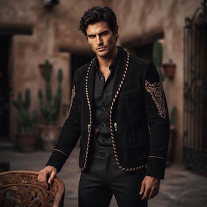 May include: A black blazer featuring a shawl collar with a brown and black striped trim, long sleeves with intricate brown embroidery on the shoulders, and a button closure. The blazer is worn over a black button-down shirt and black trousers.