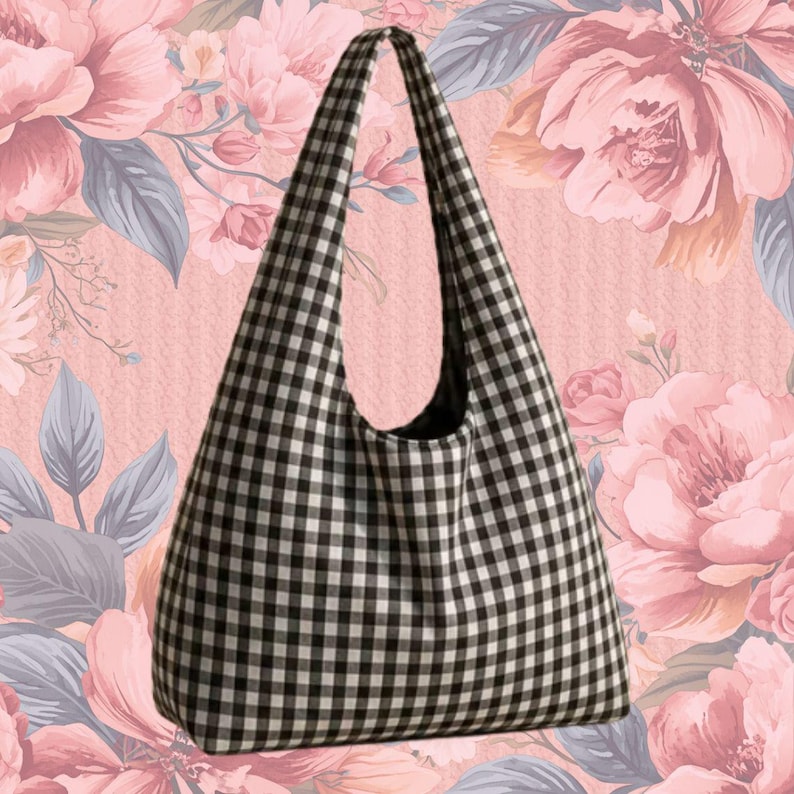 May include: A hobo-style shoulder bag featuring a black and white gingham check pattern. The bag has a single integrated shoulder strap and a wide, rounded opening, constructed from fabric with a consistent checkered design throughout the exterior.
