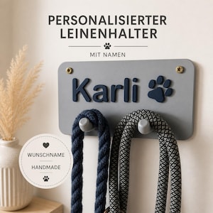 Könnte beinhalten: Ein grauer Hunde-Leinenhalter mit dem Namen "Karli" in Marineblau, einem Pfotenabdruck und zwei Haken, die Hundeleinen halten. Der Text "PERSONALISIERTER LEINENHALTER" und "MIT NAMEN" stehen oben.