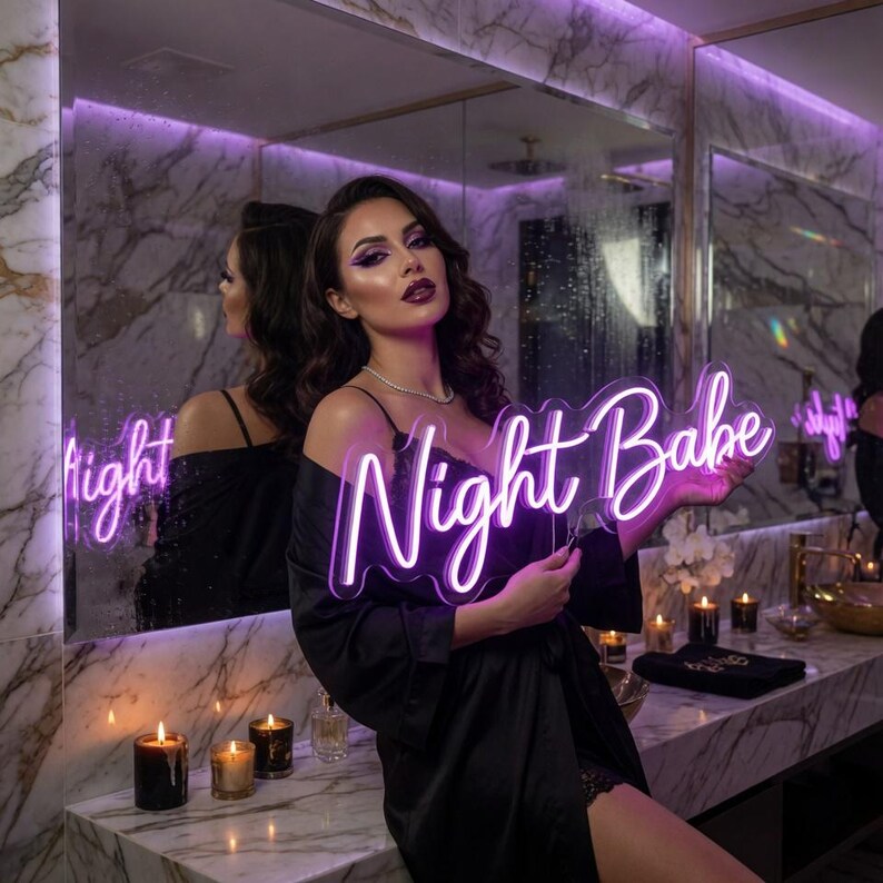 May include: A custom neon sign featuring the text Night Babe in a bright purple script font. The sign is constructed with clear acrylic backing and illuminated tubing, designed to be held or mounted as a decorative wall piece for interior spaces.