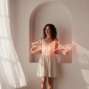 Pu&ograve; includere: Una donna in un vestito chiaro tiene in mano un'insegna al neon con la scritta "Easy Days". L'insegna si illumina con una luce calda e invitante. Lo sfondo presenta un'alcova ad arco e una finestra con tende trasparenti.
