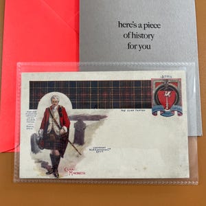 Puede incluir: Una tarjeta con una ilustración de un hombre con vestimenta escocesa tradicional, con un abrigo rojo y un kilt. La tarjeta incluye el texto "Clan Macbeth" y "The Clan Tartan". El fondo incluye un patrón de tartán y el texto "here's a piece of history for you."