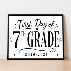 May include: A rectangular black frame containing a white sign with black text that reads First Day of 7th GRADE 2026-2027. The design features decorative flourishes, small hearts, and lines surrounding the bold, centered lettering.