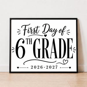 May include: A rectangular black frame containing a white sign with black text that reads First Day of 6TH GRADE 2026-2027. The design features decorative flourishes, small hearts, and lines surrounding the bold, centered lettering.