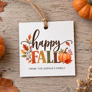 May include: A square white gift tag with a jute twine loop featuring the text happy FALL in brown and multicolored block letters. The design includes watercolor illustrations of orange pumpkins, red berries, and autumn leaves with the text FROM: THE SOPHIA'S FAMILY.