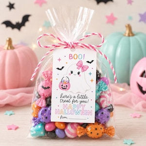 Puede incluir: Una bolsa de pl&aacute;stico transparente llena de dulces coloridos, atada con un cordel a rayas rosas y blancas. Una etiqueta blanca rectangular muestra un fantasma de dibujos animados con un lazo rosa, un cubo de calabaza y el texto BOO! here's a little treat for you! HAPPY HALLOWEEN from.