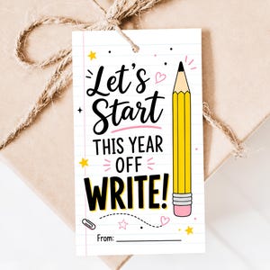 May include: A rectangular gift tag with a white lined paper background featuring a yellow pencil illustration and the text Let's Start THIS YEAR OFF WRITE! with small pink hearts, yellow stars, and a paperclip icon, finished with a twine string.