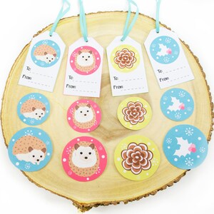 May include: Set of 10 gift tags and stickers featuring a hedgehog, flower, and holly designs. The tags are white with black lines and the stickers are round with a white background and colorful designs.