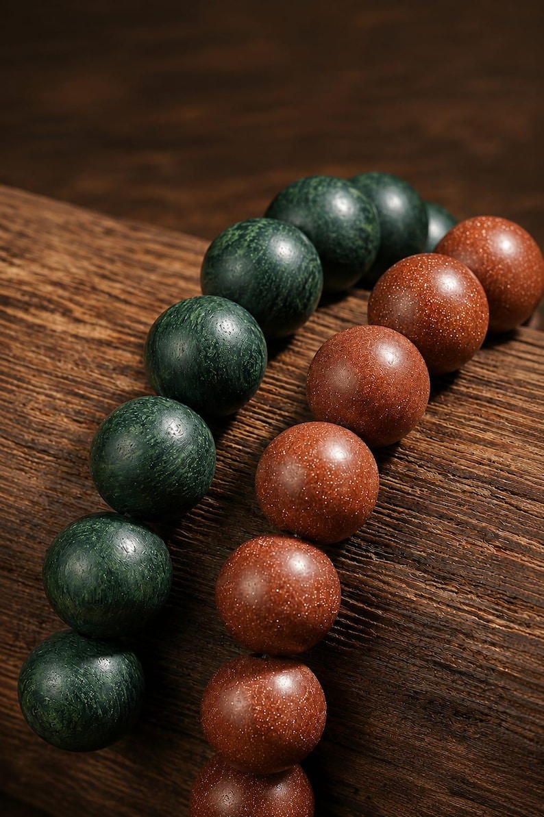 May include: Two strands of spherical beads arranged in parallel lines. One strand consists of dark green, textured, matte-finish beads, while the other strand features shimmering, reddish-brown, glittery beads with a smooth, polished surface.