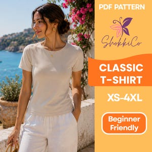 Peut inclure: Une femme porte un t-shirt classique beige et un pantalon blanc. L'image contient le texte "PDF Pattern", "ShokkiCo", "Classic T-Shirt", "XS-4XL" et "Beginner Friendly". En arrière-plan, une vue côtière avec des fleurs roses.