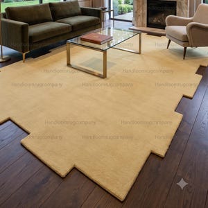 Puede incluir: Una alfombra grande de color amarillo claro sólido con un diseño de borde geométrico escalonado. La alfombra presenta una textura uniforme y afelpada, colocada sobre un suelo de madera oscura en una sala de estar con muebles.