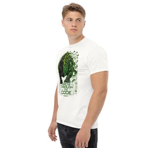 Puede incluir: Camiseta blanca con un gráfico verde y negro de una criatura y el texto "GROW THROUGH THE CODE". El diseño tiene una estética de placa de circuito. La camiseta está hecha de un material suave y cómodo.