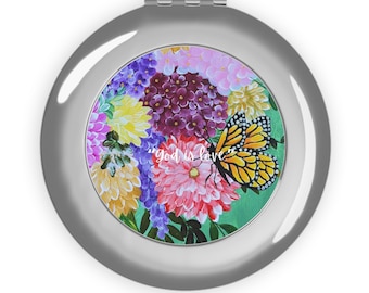 Espejo de viaje compacto con diseño de ramo floral y mariposa monarca.