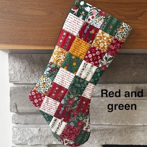 May include: A Christmas stocking constructed from a patchwork of various fabrics featuring red, green, white, and gold colors. The fabric squares display patterns of holiday figures, floral motifs, and script text. The text "Red and green" is visible.