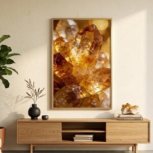 May include: A framed art print featuring a close-up of golden-brown crystals. The crystals are illuminated, creating a warm, inviting glow. The artwork is displayed above a wooden cabinet in a living room setting, with a potted plant and decorative items.