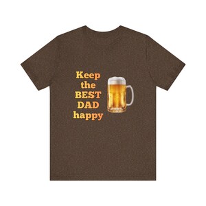 May include: Brown t-shirt with the text "Keep the BEST DAD happy" in yellow and orange. A beer mug filled with beer is to the right of the text.