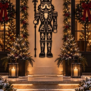 May include: A black metal wall art piece shaped like a nutcracker soldier, featuring intricate cut-out details on the uniform, hat, and staff. The silhouette displays a symmetrical design with leaf-like patterns throughout the figure's attire.