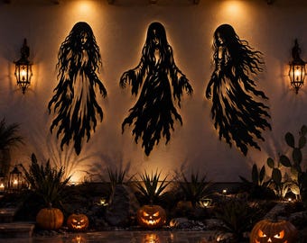 May include: Three black metal wall art silhouettes depicting ghostly figures with long flowing hair and tattered robes, mounted on an exterior wall. The figures are backlit, creating a glowing effect against the light-colored stucco surface.
