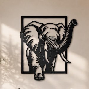 Könnte beinhalten: Ein Wandkunstobjekt aus schwarzem Metall, das die Silhouette eines stilisierten Elefanten zeigt, der aus einem rechteckigen Rahmen hervortritt. Der Elefant ist mit erhobenem Rüssel und sichtbaren Stoßzähnen dargestellt.