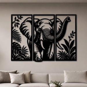 May include: A three-panel black metal wall art set featuring a detailed silhouette of an elephant surrounded by tropical foliage. The design is divided into three vertical rectangular frames, showcasing the elephant with its trunk raised.