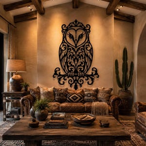 May include: A large, black, laser-cut metal wall art piece shaped like an owl with intricate, symmetrical scrollwork patterns throughout its body and wings, mounted centrally on a light-colored wall above a leather sofa in a living room.