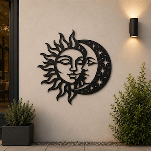 May include: Black metal wall art depicting the sun and moon with faces, set against a light-colored wall. The sun has radiating flames, and the moon is adorned with stars. The artwork is mounted near outdoor greenery and a wall-mounted light fixture.