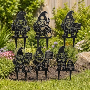 May include: A set of black metal garden gnomes with different poses and signs. The signs read "DON'T TOUCH ME", "GNOME SWEET GNOME", "GO FUCK YOURSELF", and "GO AWAY I'M GROWING". The gnomes are displayed in a garden, surrounded by plants.