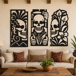 May include: A set of three black laser-cut wall art panels featuring intricate skull designs. The left panel shows a skull with a feathered headdress, the center panel depicts a skull holding corn, and the right panel displays a skull with lilies.
