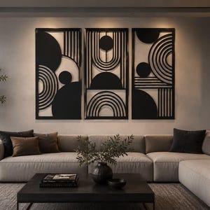 Op de afbeelding: Een set van drie rechthoekige zwarte wandpanelen met geometrische uitsparingen van cirkels, halve cirkels en verticale lijnen. De panelen zijn naast elkaar geplaatst en tonen een consistent patroon van solide vormen en lijnen.