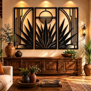 Op de afbeelding: Een driedelig zwart metalen wandkunstwerk met een geometrisch ontwerp met een zon en een agaveplantmotief. Het kunstwerk wordt tentoongesteld boven een houten kast in een goed verlichte woonkamer. Decoratieve vazen en planten zijn ook aanwezig.