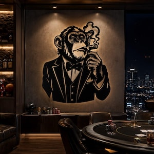 May include: A large, black, wall-mounted metal silhouette of a chimpanzee wearing a tuxedo, bow tie, and smoking a cigar, with backlighting creating a glowing halo effect against a textured gray wall in a room with a poker table.