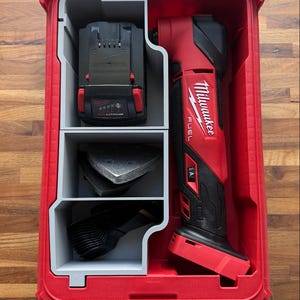 Può includere: Un utensile multifunzione Milwaukee Fuel rosso con impugnatura nera, batteria e accessori per levigatura organizzati in una valigetta di plastica rossa con divisori grigi. L'utensile presenta il logo Milwaukee Fuel in bianco sul lato.