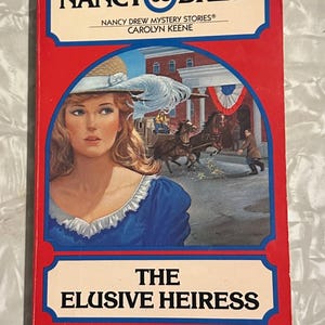 May include: A vintage Nancy Drew mystery book titled "The Elusive Heiress." The cover features a woman in a blue dress and a straw hat, with a horse-drawn carriage in the background. The book is red with blue and white accents.