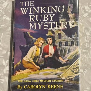May include: The Winking Ruby Mystery book cover features two girls in front of a crumbling castle. The book is part of The Dana Girls Mystery Stories series by Carolyn Keene.