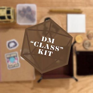 May include: A DM Class Kit featuring a brown notebook with stickers, a small yellow chest, a clear plastic container with dice, a white square card, a brown folding dice tray, a black pouch, and metallic coins, all arranged on a wooden surface.