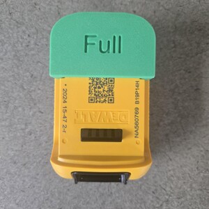 May include: A yellow and green DeWalt battery level indicator. The top is green and reads "Full" in white. The yellow body has the DeWalt logo, a QR code, and other text. The bottom has a black connector.