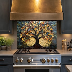 May include: A kitchen backsplash featuring a mosaic-style tree with a dark brown trunk and branches adorned with multicolored leaves in shades of orange, yellow, blue, and green, positioned behind a stainless steel gas range and oven.