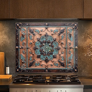 May include: A rectangular metal backsplash panel featuring a central floral motif in oxidized copper and teal green tones. The design includes intricate scrollwork, raised relief patterns, and a dark metallic frame, mounted on a kitchen wall.