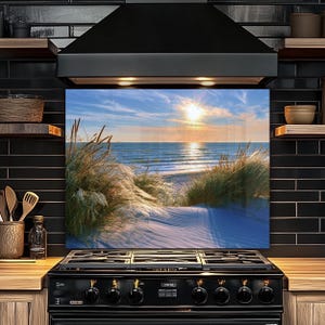 May include: A scenic beach landscape with a bright sun setting over the ocean. The image features a sandy path leading to the water, framed by tall, green grasses. The sky is a mix of blue and white clouds.