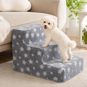 May include: A three-step pet staircase covered in a plush, grey fabric featuring a repeating pattern of light-colored stars. The steps are designed to assist small animals in reaching elevated surfaces like furniture, with a soft, textured finish.