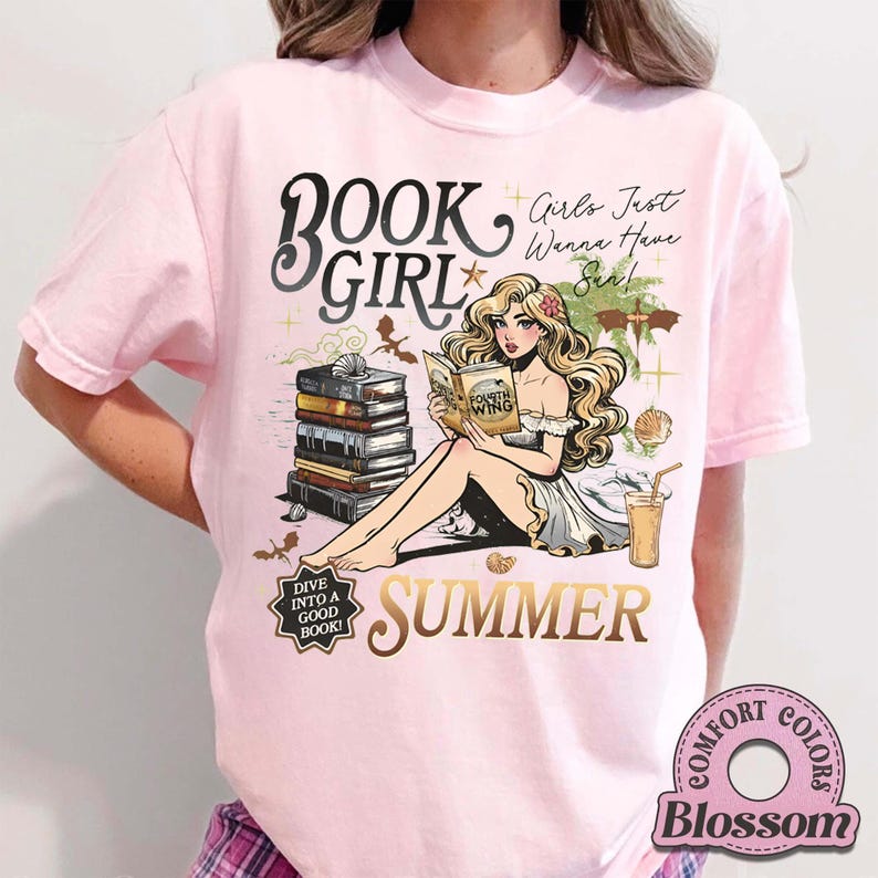 May include: A pale pink t-shirt with a graphic of a woman reading, with the words "Book Girl Summer". The design includes books, seashells, and a drink, with the text "Dive into a good book!"