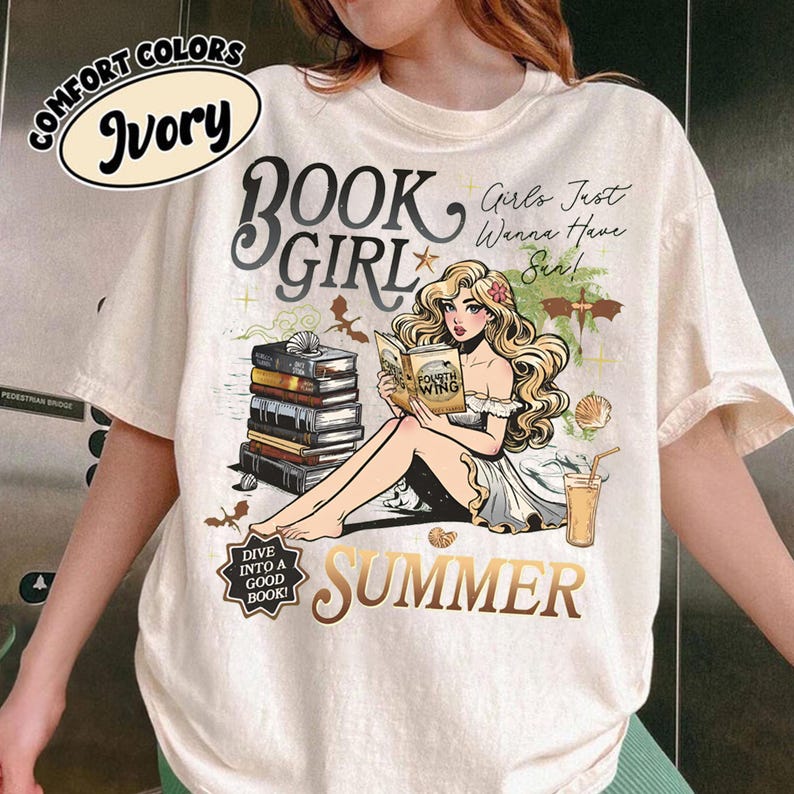 May include: Ivory t-shirt featuring a graphic of a woman reading a book, stacked books, and the words "BOOK GIRL SUMMER." The shirt also features the text "Girls Just Wanna Have Sun!" and "Dive Into A Good Book!"