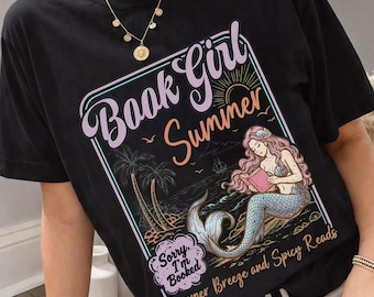 May include: Black t-shirt with a graphic featuring a mermaid reading a book on a beach, with the words "Book Girl Summer" and "Summer Breeze and Spicy Reads." The design includes palm trees, a ship, and the text "Sorry, I'm Booked."