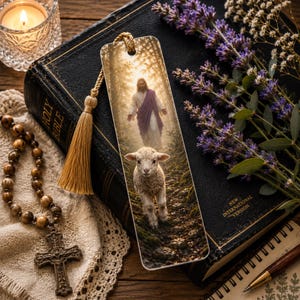 May include: A rectangular bookmark featuring a printed image of a lamb walking on a forest path with a figure in a white robe and purple sash standing behind it. The bookmark has a gold-colored cord tassel attached to the top center hole.