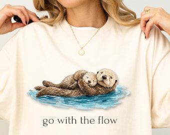 Camiseta "Go With The Flow" con nutria, linda camiseta de nutria marina, camiseta divertida de animales, estampado vintage del océano, regalo para amantes de la naturaleza, camiseta unisex con estética retro.