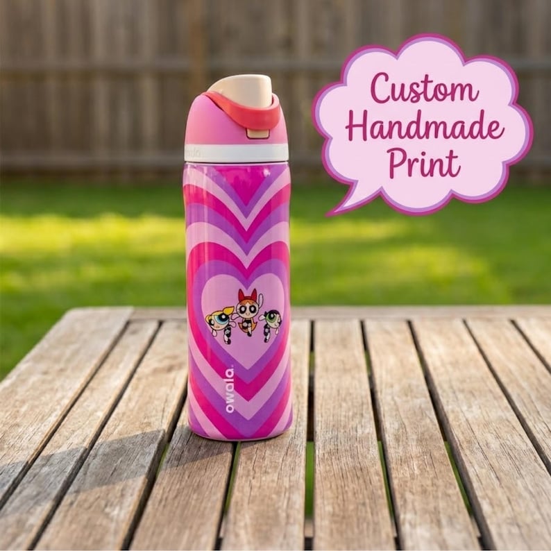 May include: A pink and purple water bottle with a heart-shaped design and a cartoon graphic. The bottle has a pink lid and a flip-top opening. The text "Custom Handmade Print" is in a pink speech bubble.