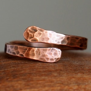 Può includere: Un anello in rame martellato con un design attorcigliato. L'anello è realizzato in un unico pezzo di rame che è stato martellato per creare una superficie testurizzata.